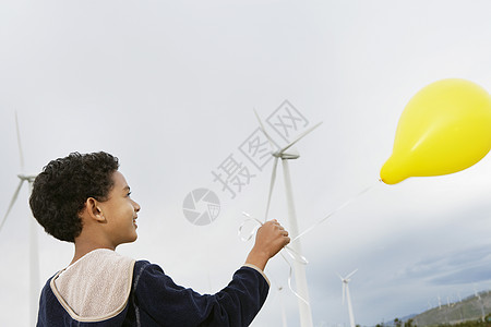 非裔美国男孩在风力农场玩黄气球的游戏图片
