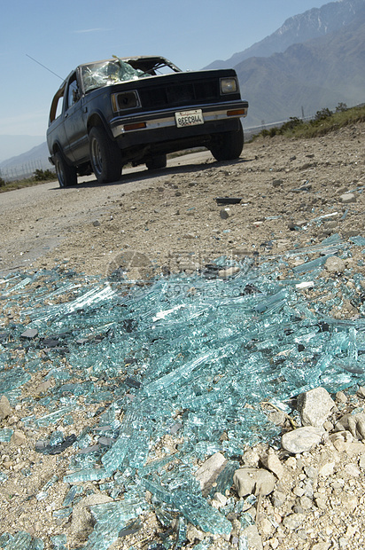 土面上断断的挡风玻璃碎片和背景被损坏的卡车图片