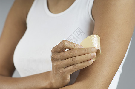 一名非洲裔美国妇女将尼古丁贴在手臂上的中产体图片