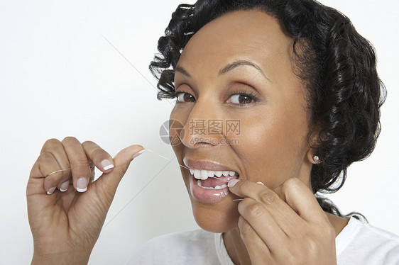 一位非裔美国女性在白色背景下牙刷牙齿的近镜肖像图片