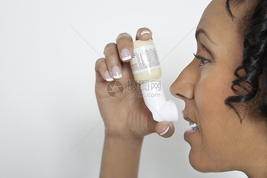 一名非裔美国女性在白背景使用吸入器的侧面视图图片