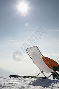 在雪中坐在草椅上的人服装太阳天空躺椅地平线风景降雪胜地滑雪一人图片