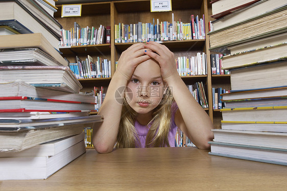 坐在书桌上的女学生和图书馆肖像中的书籍图片