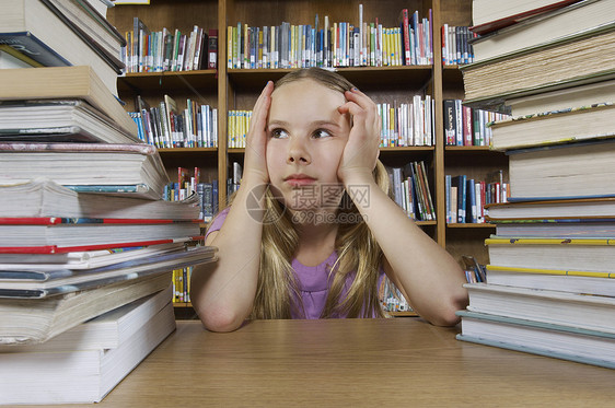 女孩坐在书桌和图书馆书籍的女学生长发书架想像力青春期瞳孔沉思学校图书服装童年图片