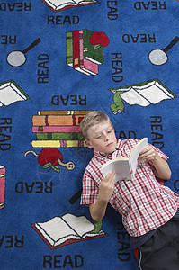 在图书馆的地板上读书的男学生背景图片