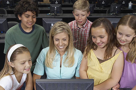 在校儿童与教室教师一起使用计算机教学的儿童图片