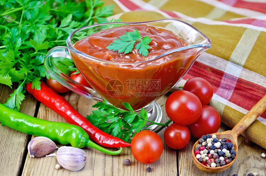 在玻璃肉汁船上加蔬菜的番茄酱在板上图片
