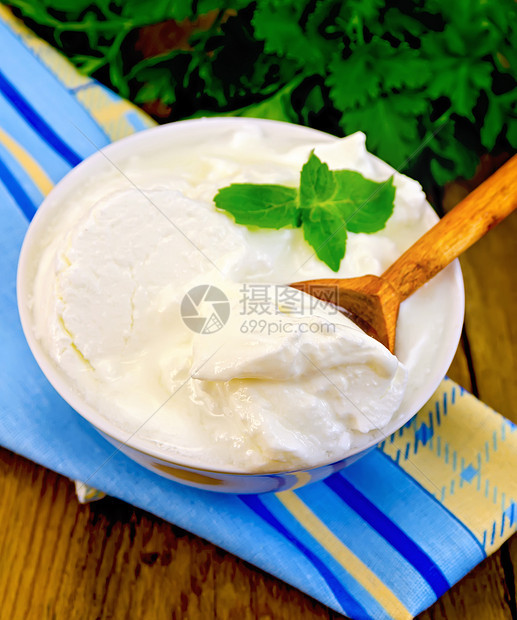 用木勺子和薄荷糖在白碗中的酸奶图片