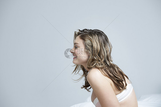 穿着内裤 在床衣上微笑的年轻女性概况图片