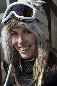 穿着护目镜和毛皮滑雪帽的快乐的女性滑雪者肖像图片