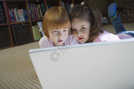 女孩(5-6)躺在地板上 使用笔记本电脑思考图片