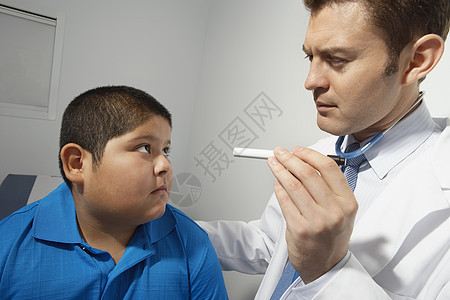 男性医生在诊所对男孩的眼睛进行光照图片