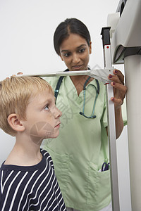 测量诊所中男孩身高的女医生;图片