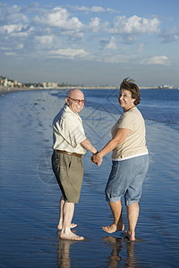 老年夫妇在海滩上行走 回头看图片