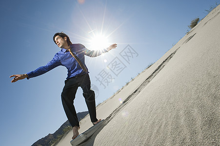 商务人士冲浪下山 在沙漠的短小案例图片