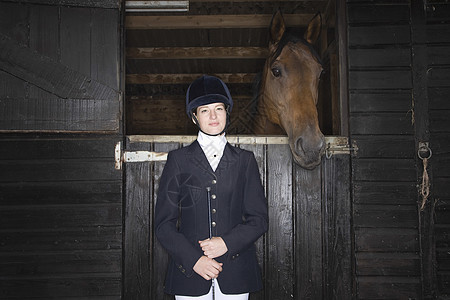 骑马的女性骑马手的肖像 马匹稳定鞭子女孩动物友谊工作骑马帽夹克团结水平木头图片