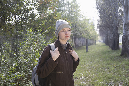在公园穿冬衣的年轻妇女休闲薄雾树木活动成年背包孤独服装女性沉思图片