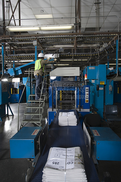 一名在印刷厂工作的人的近视景衣服机械打印机男人生产印刷报纸机器技术员操作员图片