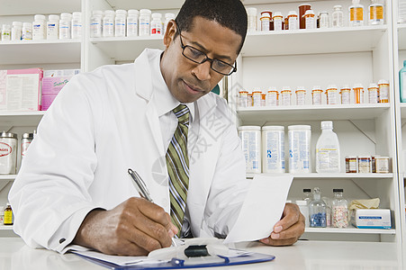 非裔美籍男药剂师在药店工作处方水平工作服货架专注男人补给品经销商药品架子图片