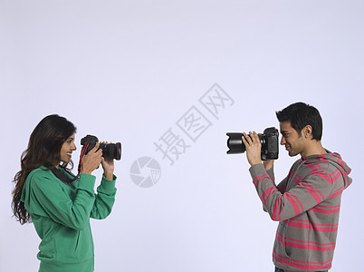 年轻女人和年轻男人拍相片的拍摄室镜头女性乐趣创造力男子成年专注微笑头肩影棚个人图片