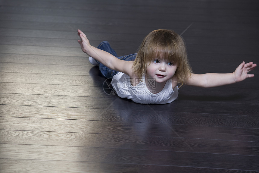 小女孩躺在地板上做运动和操练图片