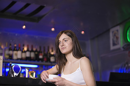 在酒吧喝茶的年轻女子头发成年长发头肩女性杯子棕色沉思活动咖啡店图片