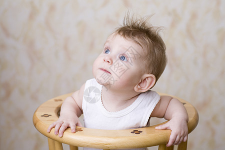 婴儿男孩坐在高椅子上 抬起头来图片