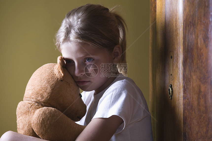 女孩在家里拥抱泰迪熊马尾辫休闲沉思乡愁童年玩具熊想像力玩具青春期活动图片