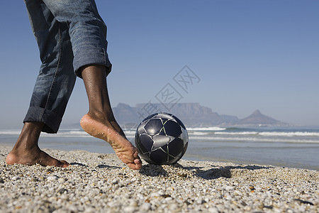 一个在海滩上踢足球的男人的低血块图片