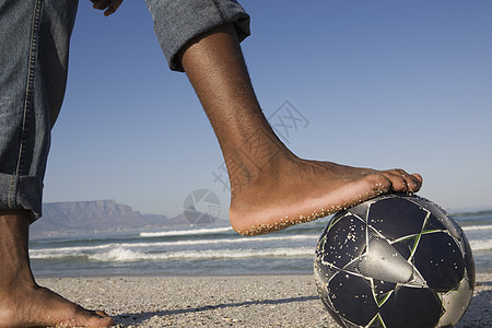 沙滩上足球球赤脚的近距离侧观图片