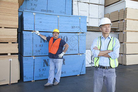 男仓库工人站在一堆胶合板前的木头前面图片