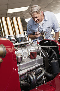 高级男子在汽车修理店看汽车发动机的年长男子图片