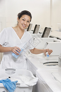 一位快乐的女员工在洗衣机里倒洗涤剂的肖像图片