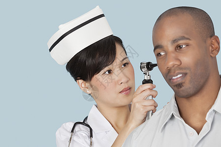 护士检查男性病人耳朵轻蓝底浅蓝色背景的耳部程序影棚制服医生女性男士治疗医疗两个人药物治疗图片