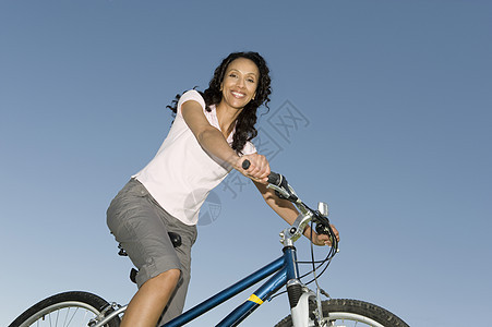 女人坐在山上骑着摩天车 与清蓝的天空对抗图片