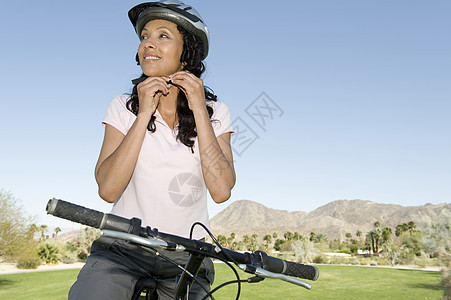 妇女调整自行车头盔闲暇活动天空短裤棕色卷发女性中年意识农村图片