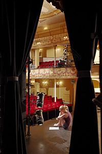 一个年轻女士坐在舞台上 带脚本的全长侧观背景图片