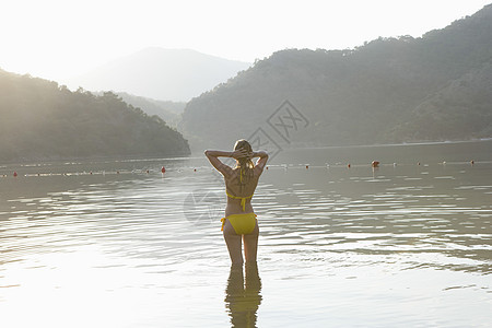 黄色比基尼妇女站在湖边游泳衣水面成人游泳女士头发乡村休闲码头双手图片