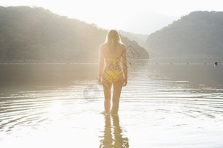黄色比基尼妇女站在湖边女子孤独水面休闲女士森林农村林地码头同心圆图片