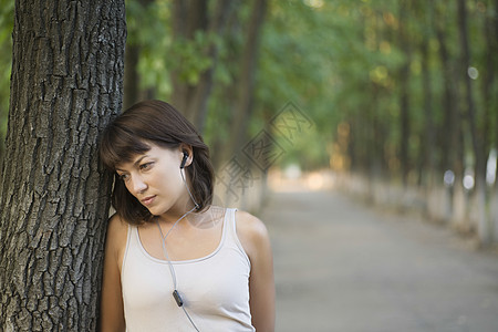 妇女在公共公园听个人立体声耳机公共公园女士沉思女性音乐娱乐头肩日光休闲图片