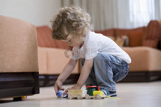 金发小子在地板上玩玩具火车图片