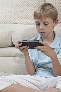 男孩坐在跨腿的手提式游戏控制台上图片