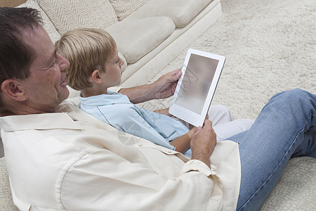 父亲和儿子读一本数字书技术家庭生活房子男人家庭显示屏设备客厅两个人时间图片