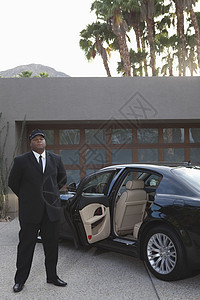 司机站在豪华车的敞开汽车门前员工车门车辆房子正装外观套装职业车道男人图片
