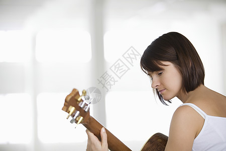 女人坐在音乐吉他手旁双肩原声练习演奏女士成人女子短发乐器仓库图片