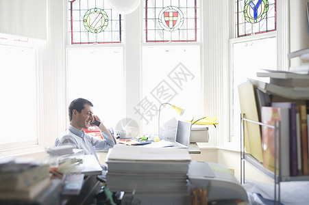 商务人士在海湾窗口的办公桌工作彩色手肘学习椅子书柜玻璃衬衫男人头肩家居背景图片