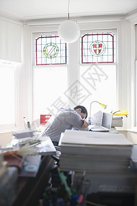 成年中年男子睡在办公桌前图片
