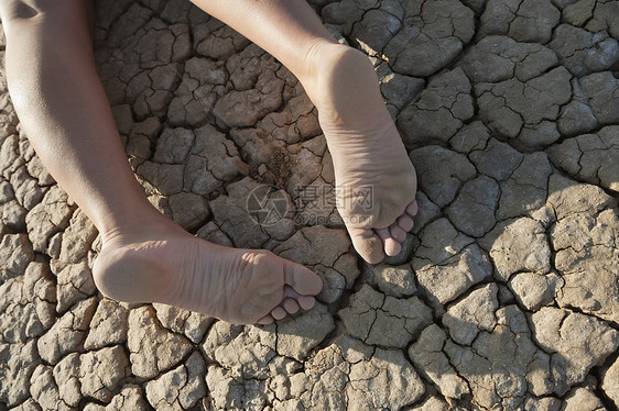 躺在破碎土地上的低层妇女女性特写说谎棕榈成年干旱疲倦赤脚沙漠视图图片