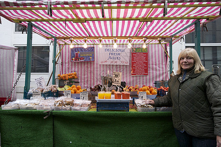 一位快乐的资深水果摊店主站在市场上的肖像图片