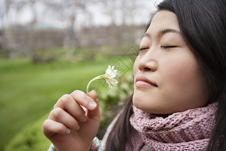 一名亚洲年轻女子在公园闻花香的近身图片